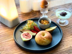 黒いプレートにベーグル、サラダ、ヨーグルト、いちじくを盛りつけた朝食