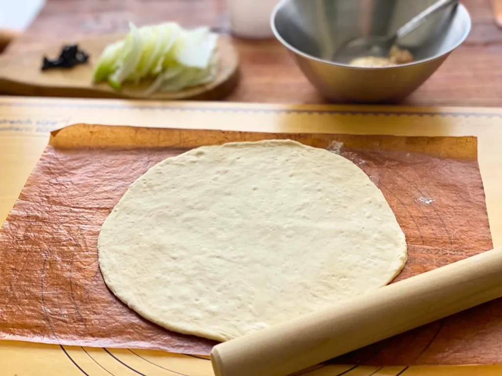 パン生地を麺棒でピザ用丸く広げる　