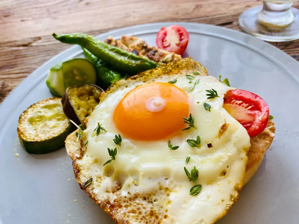 厚切りトーストに目玉焼きと彩り野菜をのせた朝食