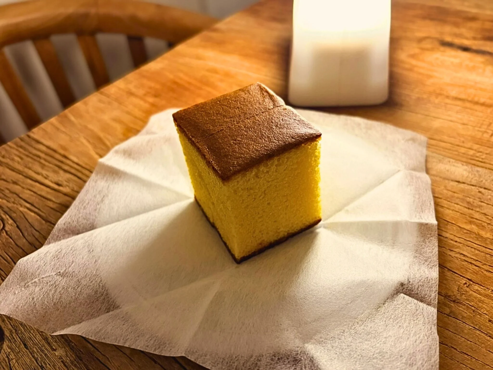 福砂屋のカステラのキューブ。紙の上に置いた一切れの断面が見える