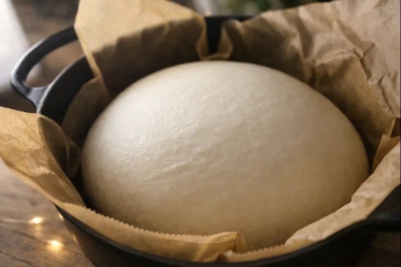 発酵を終えたこねないパンの生地。クッキングシートを敷いた鍋の中で、月のように白く静かに膨らんでいる様子