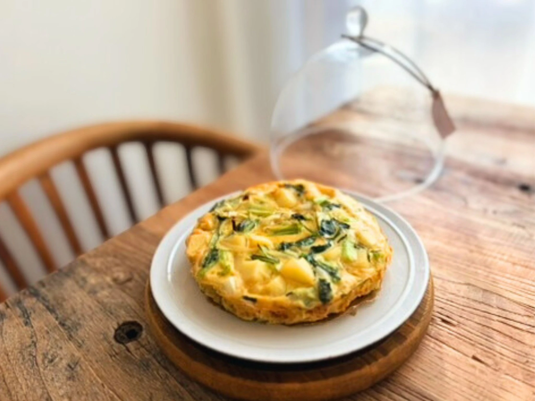木のテーブルに卵と野菜のケーキをのせた朝の風景