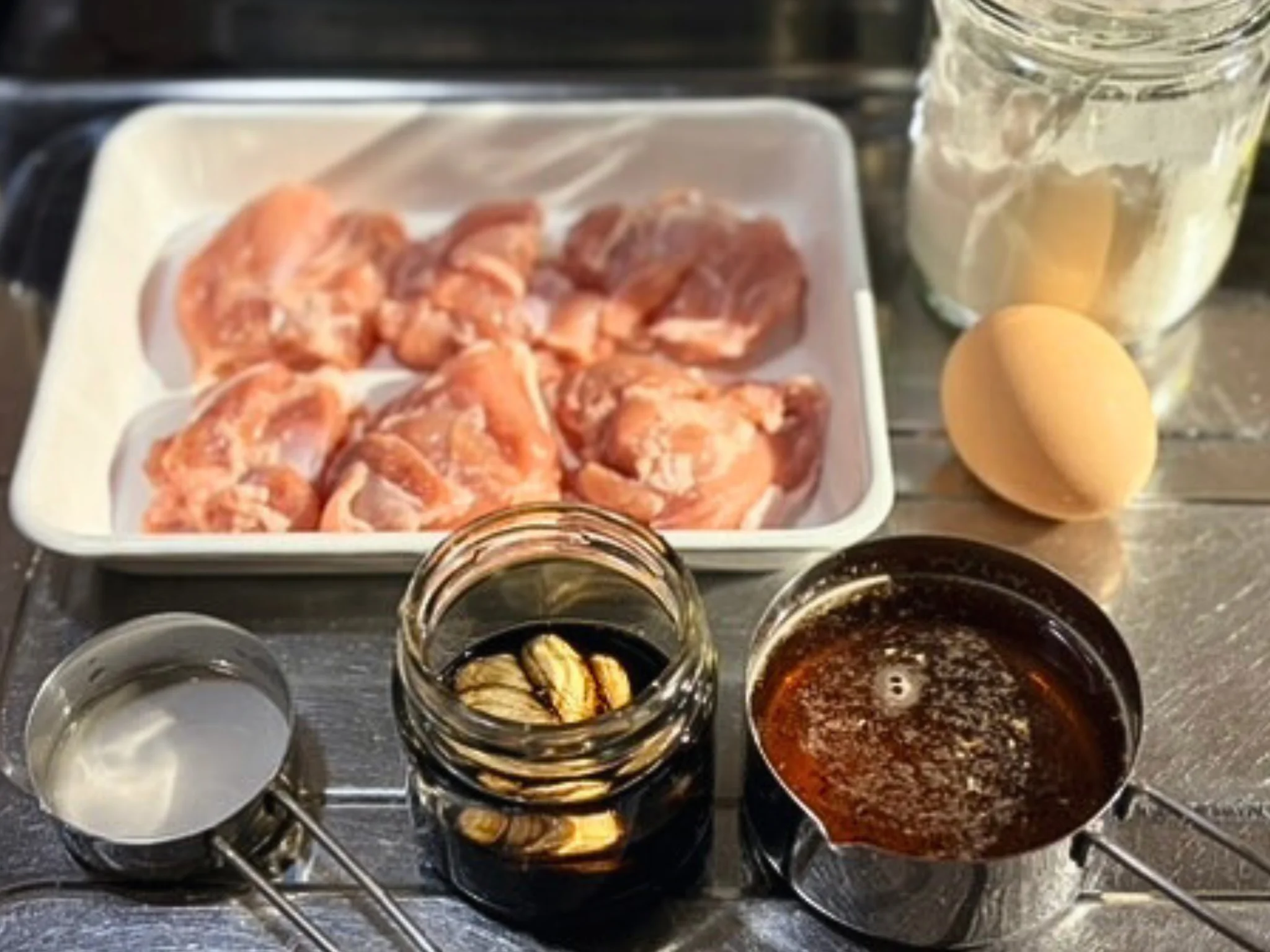 鶏から揚げの卵どんの材料。鶏もも肉、卵、にんにく醤油、ご飯などを並べた様子