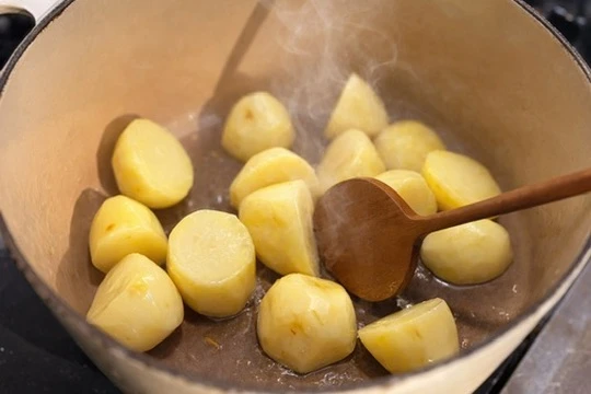 鍋の中でじゃがいもを炒めている様子。湯気が立ちのぼり、静かな台所の時間が流れている