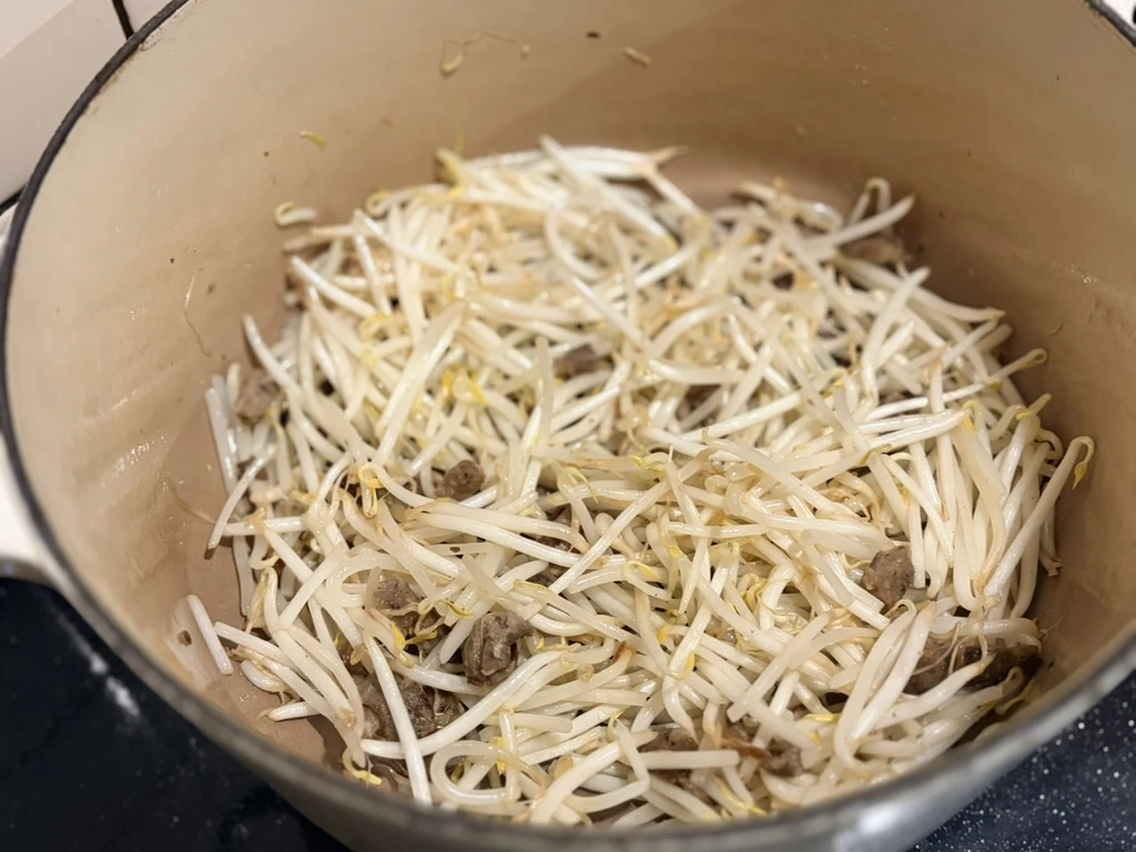 もやしとソーセージを炒めている調理途中の様子。湯気の立つル・クルーゼ鍋