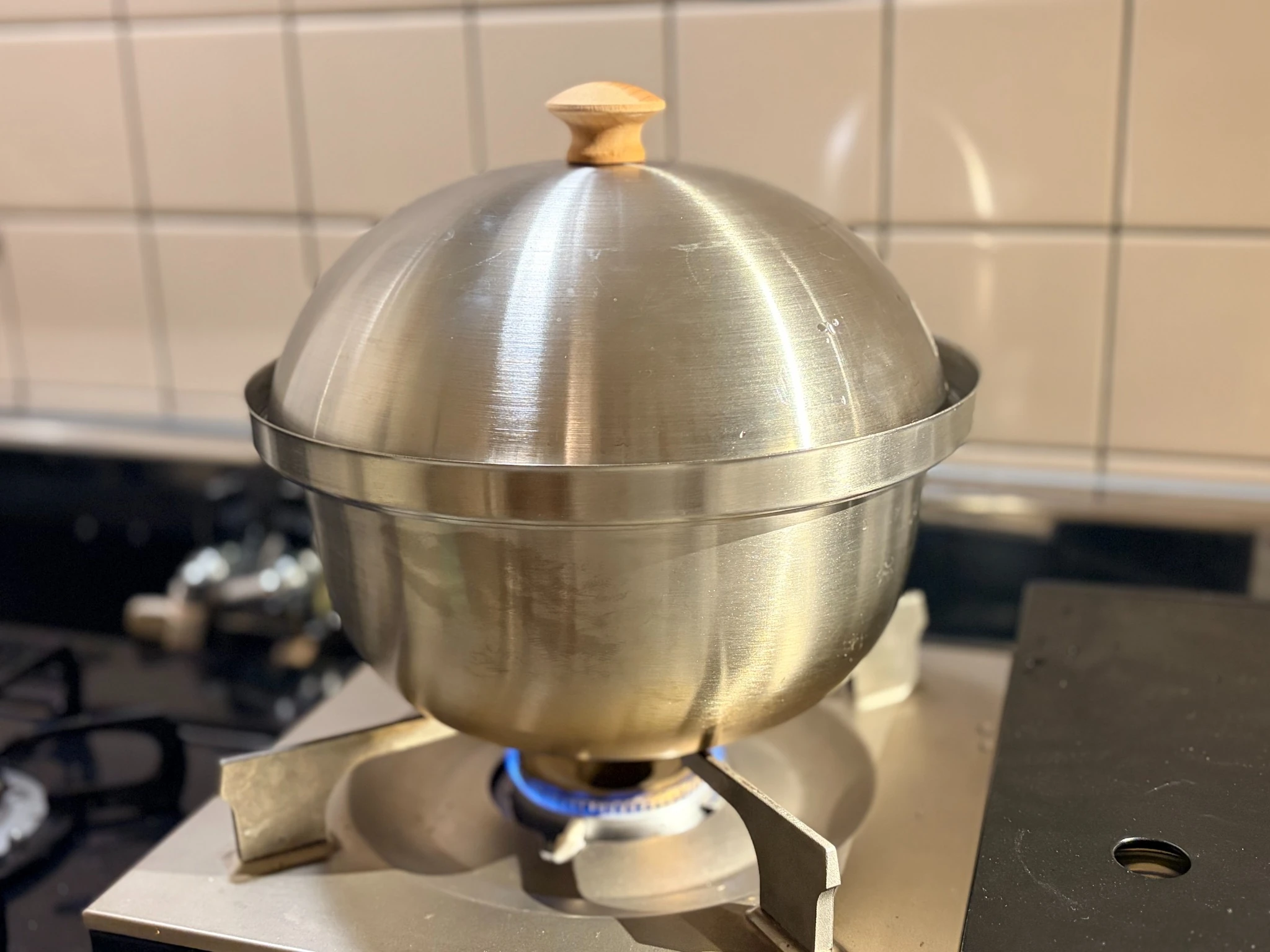 コンロの上で燻製中のステンレス製スモーカー。静かに火を入れ、ソーセージを燻している様子