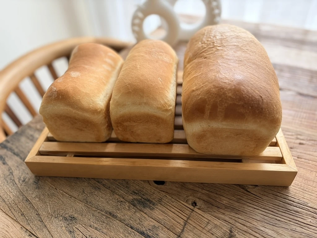 Betty Crocker Traditional White Bread。焼き上がった黄金色の食パンが木のトレーの上に並んでいる。