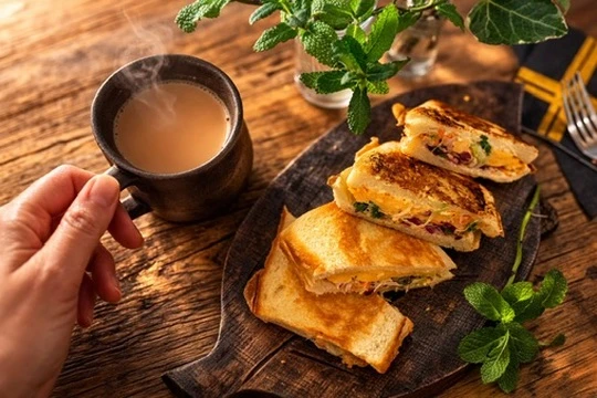 木のテーブルにホットサンドとマサラチャイを用意し、部屋を少し暗くして映画を観る雨の夜の軽食