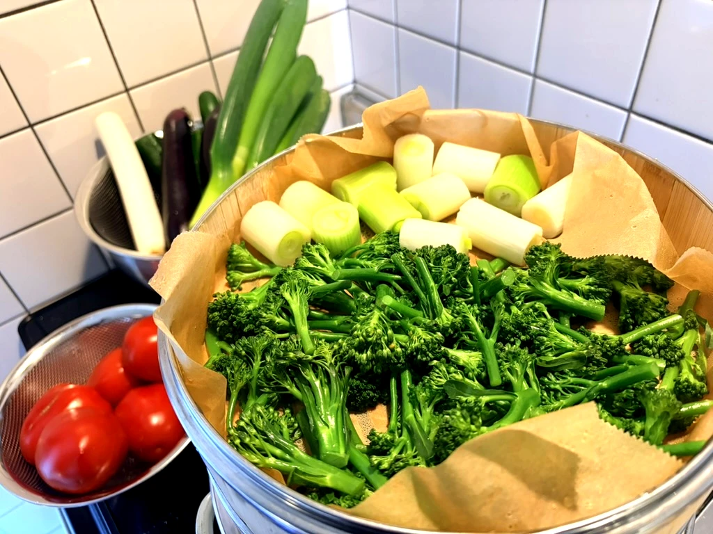 せいろにクッキングシートを敷き、ブロッコリーと長ネギを並べて蒸している様子