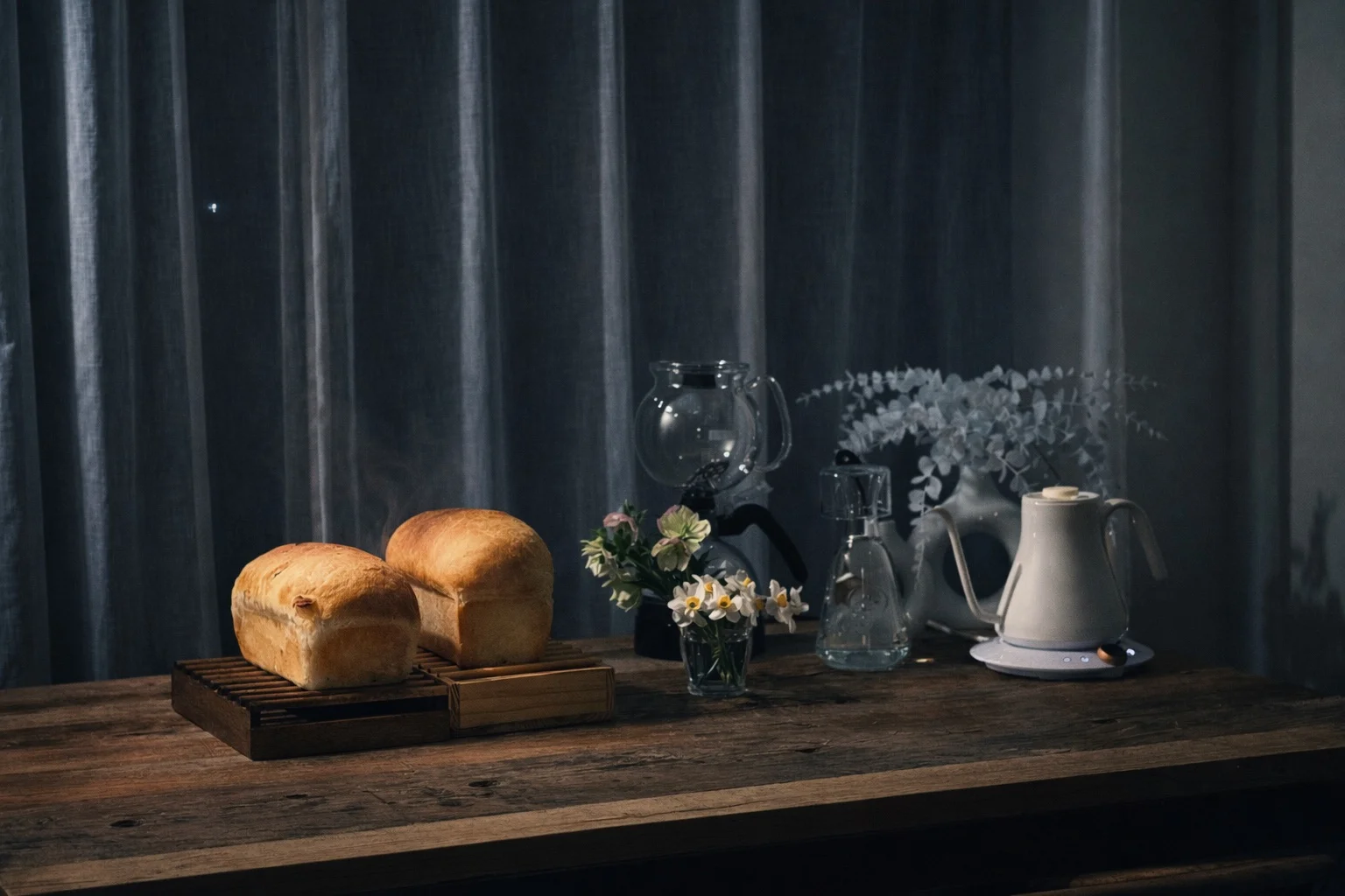 夜に焼き上がった食パンと、サイフォン、花、ケトルが並ぶ静かなテーブル