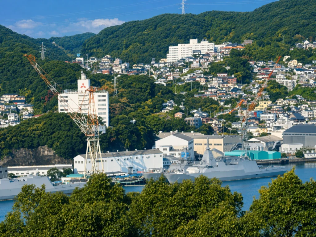 長崎港の眺め。緑の丘と造船所のクレーンが見える晴れた日の風景。