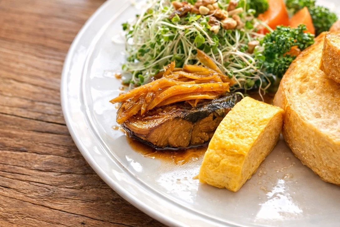 太めの生姜をのせたさばの味噌煮と、だし巻き卵を添えた朝食のアップ写真